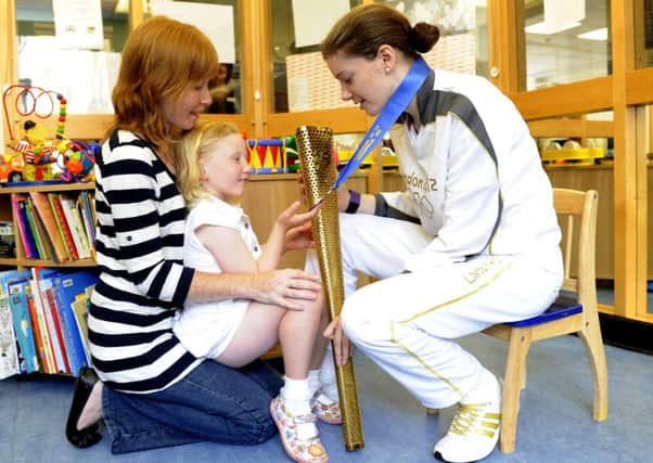 Katie Ford shows the Olympic torch to six-year-old Rachel Macleod with mum Helen at the Sick Kids. Picture: Esme Allen