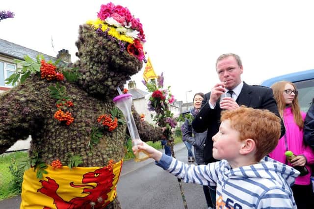 Seven-year-old Charlie Cleg gives the Burryman - Andrew Taylor - a drink. Picture: Lisa Ferguson