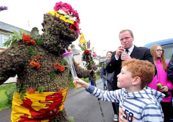 Seven-year-old Charlie Cleg gives the Burryman - Andrew Taylor - a drink. Picture: Lisa Ferguson