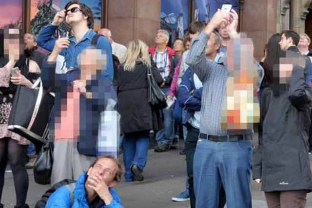 Onlookers take pictures of the man on the Scott Monument on their mobile phones. Picture: Jane Barlow