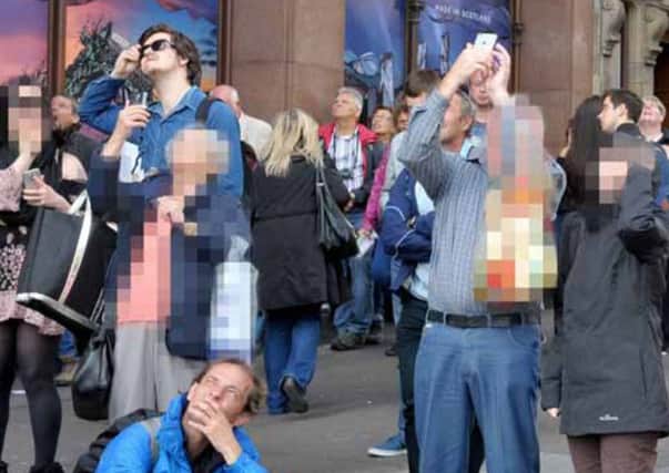 Onlookers take pictures of the man on the Scott Monument on their mobile phones. Picture: Jane Barlow