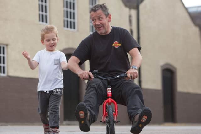 Steve Hind from the Bike Station  tries out a balance bike with the help of three-year-old Jayden Coll. Picture: Toby Williams