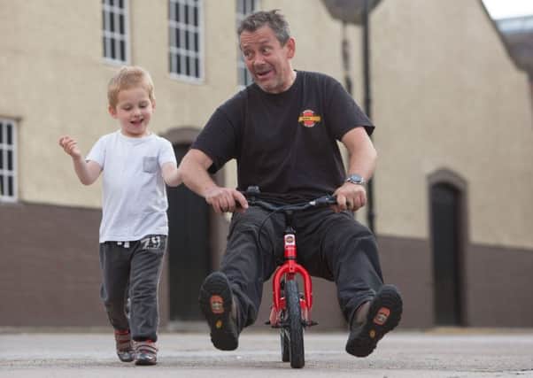 Steve Hind from the Bike Station  tries out a balance bike with the help of three-year-old Jayden Coll. Picture: Toby Williams