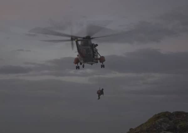 The helicopter crew lift the man from the rocks. Picture: David James Carr