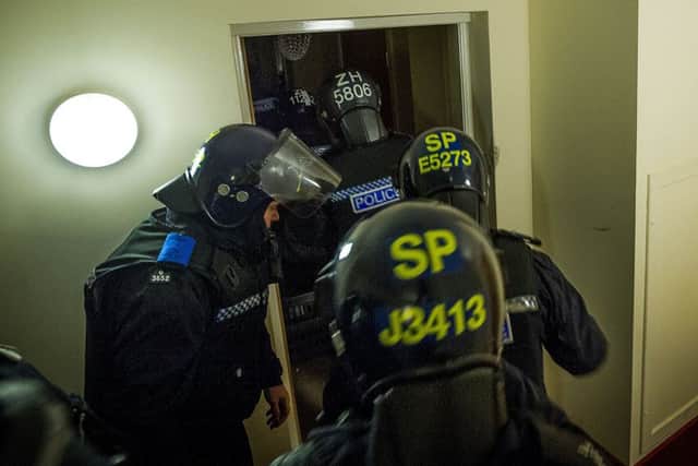 Police in riot gear storm a flat early yesterday morning as part of the raids. Picture: TSPL