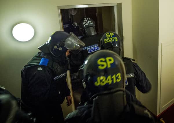 Police in riot gear storm a flat early yesterday morning as part of the raids. Picture: TSPL