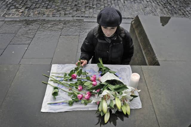 Members of the public stop to read and add to a small floral tribute left outside the Cathedral. Picture: Neil Hanna