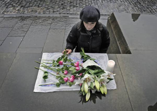Members of the public stop to read and add to a small floral tribute left outside the Cathedral. Picture: Neil Hanna