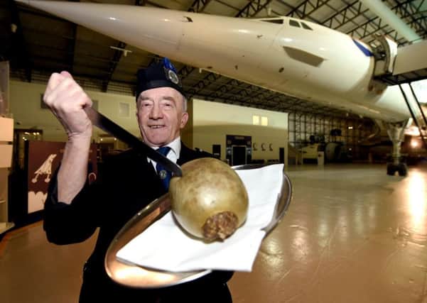 Piper David Leckie from Haddington Pipe Band tucks into a haggis in the shadow of Concorde at the Museum of Flight. Picture: Lisa Ferguson