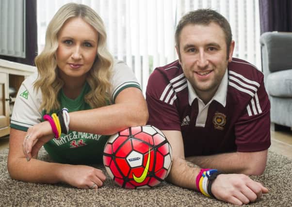 Hibs fan Kathleen Fraser and her Jambo husband Paul are promoting unity bands for World Cancer Day. Picture: Lesley Martin
