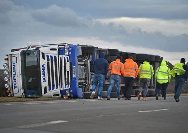 Truck drivers walk past an overturned lorry blocking the A1 in Torness. Picture: Getty Images