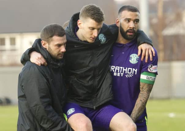 Paul Hanlon is carried off the field by team-mates Kevin Thomson and Liam Fontaine