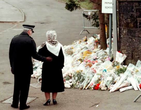 A woman and police officer pay their respects in Dunblane in 1996. Picture: Getty