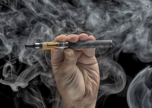 Hand holding an electronic cigarette over a dark background