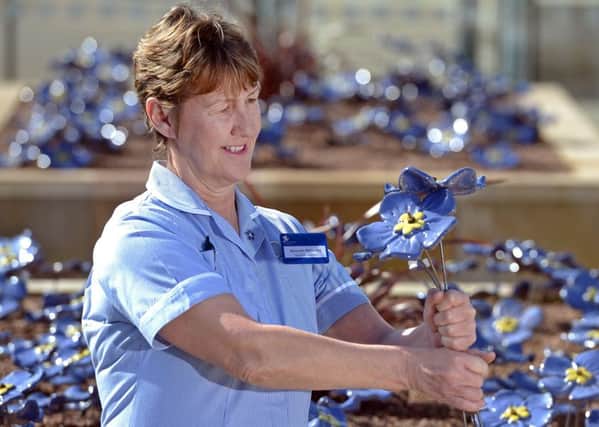St Columba's Nursing Auxiliary Maureen McCaskey plants a ceramic flower in the Tribute Garden. Picture: Neil Hanna