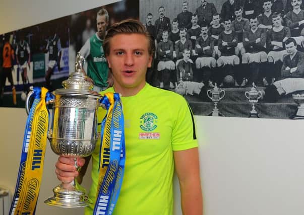 Jason Cummings, pictured next to a shot of the last Hibs team to win the Scottish Cup way back in 1902, wants to go down 
in the club's folklore. Pic: Eric McCowat
