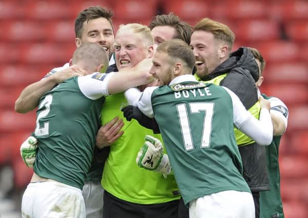 The Hibs players mob Conrad Logan after his penalty shoot-out heroics. Pic: Neil Hanna