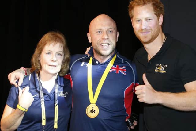Prince Harry poses for a photo after presenting a gold medal to lightweight weightlifter Michael Yule and his mother Jennifer. Picture: PA