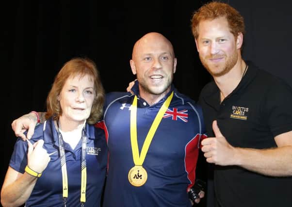 Prince Harry poses for a photo after presenting a gold medal to lightweight weightlifter Michael Yule and his mother Jennifer. Picture: PA