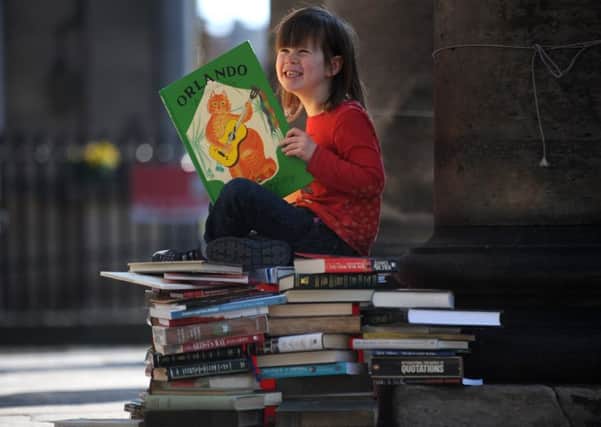 Morvan Gardner, aged four, reads on a pile of books in front of   St Andrew's and St George's West Church, where Christian Aid's charity book sale starts tomorrow. Picture: Esme Allen