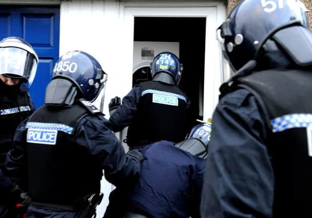 Police officers in protective helmets carry out a raid looking for drugs. Picture: Lisa Ferguson