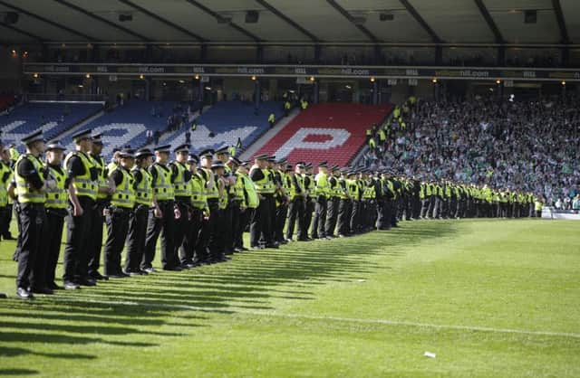 Police officers form a line on the half way line to keep rival fans apart. Picture: Neil Hanna
