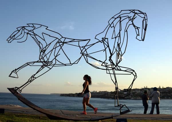 A woman walks next to an artwork by Harrie Fasher titled 'Which way forward?' at Sydney's Sculpture by the Sea exhibition. Picture: Saeed Khan/AFP/Getty Images