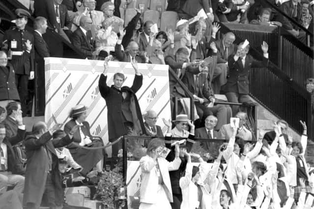 Prince Edward and some other VIPs join in the 'Mexican Wave' during the athletics at the Edinburgh Commonwealth Games 1986, held at Meadowbank stadium. The Queen remains seated.