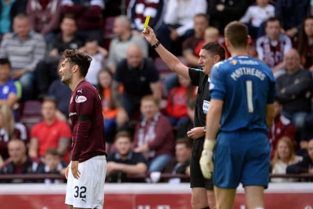 Tony Watt walks away as referee Craig Thomson brandishes the yellow card
