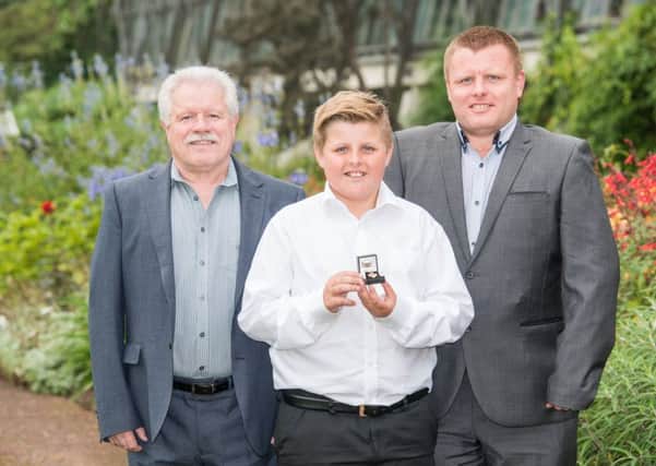 The family of Elaine Moodie receive a posthumous honour on her behalf after she donated her organs to help others. From left, husband Thomas Allan Moodie, grandson Scott Moodie, and son Ross Moodie.