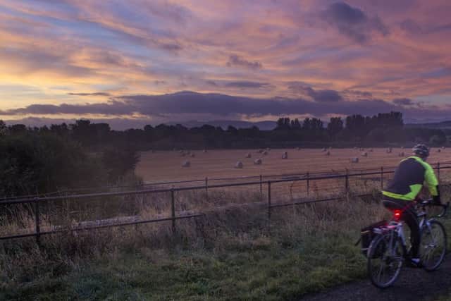 A cyclist takes in a colour full sky as the sunrises in West Lothian on an autumnal morning. Picture: SWNS