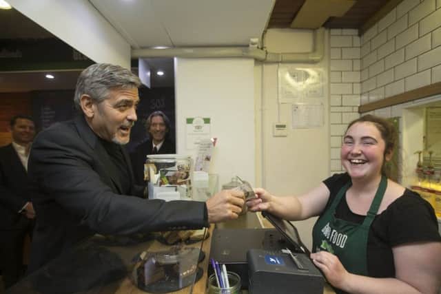 George Clooney hands over a five pound note to Ciara Whelan during his visit to Social Bite in 2015. Picture: GETTY