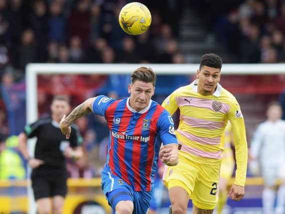 Josh Meekings of Inverness chases a through ball with Hearts striker Bjorn Johnsen