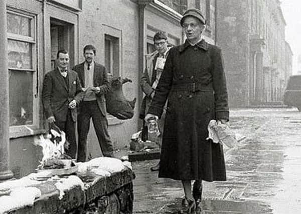 Jim Haynes, second from left, watches as the elderly lady burns her copy of Lady Chatterley's Lover outside his shop. Picture: Demarco archives.