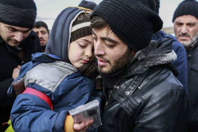 Muhammed Salih, 26, from Aleppo, Syria, holds his son, name not given, after crossing into Turkey, at the Cilvegozu border gate with Syria, near Hatay, southeastern Turkey, Sunday, Dec, 18, 2016. Several people were able to cross into Turkey after they managed to leave the embattled Syrian city. The Aleppo evacuation was suspended Friday after a report of shooting at a crossing point into the enclave by both sides of the conflict. (AP Photo/Emrah Gurel)