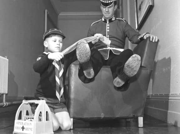 Cubs took their bob-a-job Operation Shoe-Shine to Redford barracks in March 1972. Unidentified cub scout polishing the boots of a soldier.