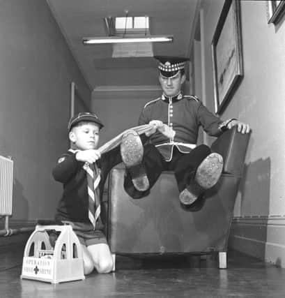 Cubs took their bob-a-job Operation Shoe-Shine to Redford barracks in March 1972. Unidentified cub scout polishing the boots of a soldier.