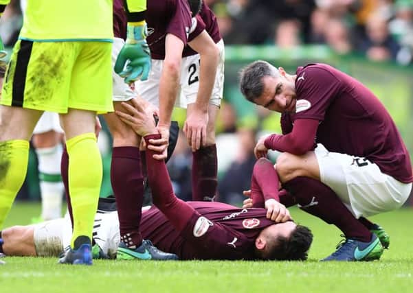 John Souttar is comforted by Hearts team-mate Aaron Hughes after suffering a serious Achilles injury during the 4-0 defeat at Celtic Park