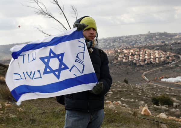 An Israeli settler holds a flag with slogans at the Amona outpost, northeast of Ramallah. Picture: AFP