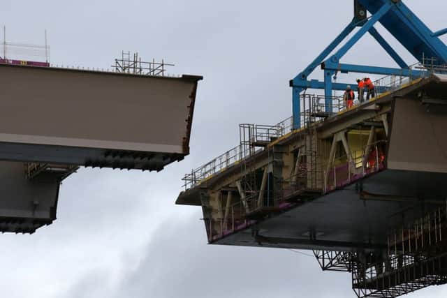 Workmen view the gap as the final deck piece of the Queensferry Crossing sits on a barge ahead of it being  lifted into position. Picture; Andrew Milligan/PA Wire