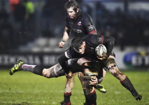 Edinburgh's Magnus Bradbury takes a hit from a flying Osprey as a team-mate struggles in the mud, behind