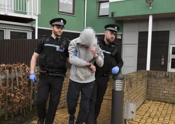 Police escort a man from a property. Pic: Andrew O'Brien