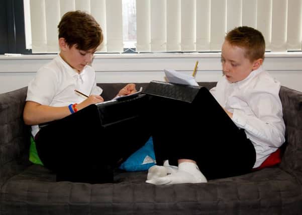 Kyle Mclay and Archie Ralph doing school work on the sofa.