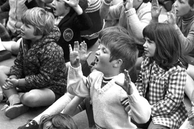 Children sitting on the paved area of the Ross bandstand join in during Children's Hour in West Princes Street gardens Edinburgh in July 1973. Picture: TSPL
