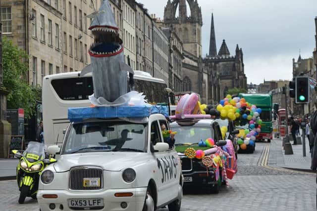 A taxi with a shark bursting out its roof leads the parade down the Royal Mile. Picture: Jon Savage