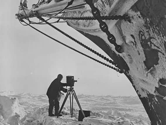 Photographer Frank Hayley seen with an early movie camera beneath the bow of the 'Endurance.'