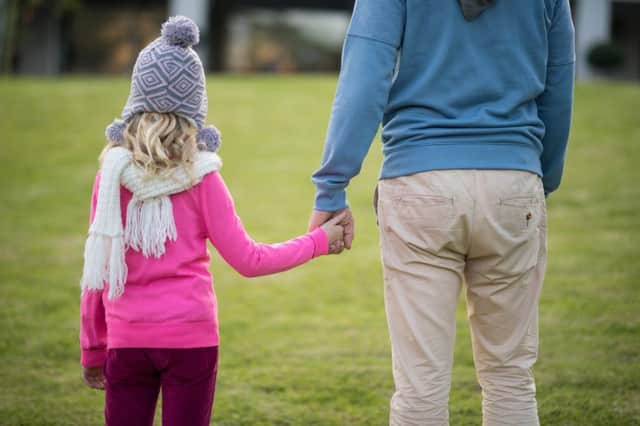 Rear view of father and daughter holding hands in the garden