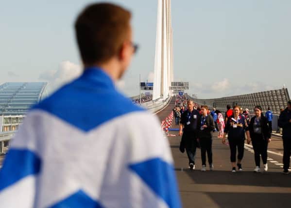 A walker draped in a Saltire crosses the new bridge during the opening celebrations. Picture: Scott Louden