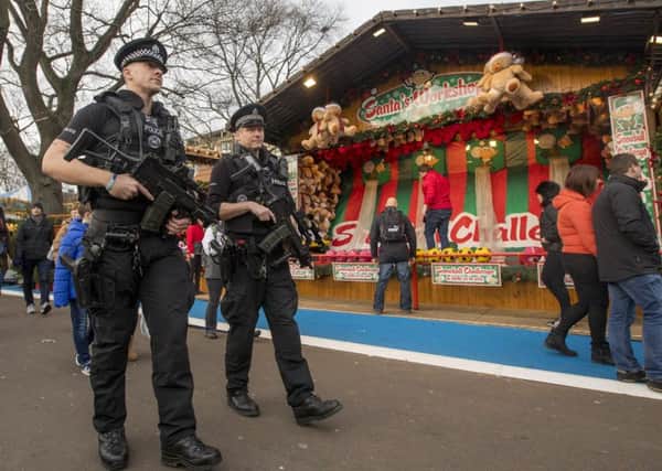 Armed Police on patrol and concrete bollards  at Edinburgh Christmas Market in Princes Street Gardens.