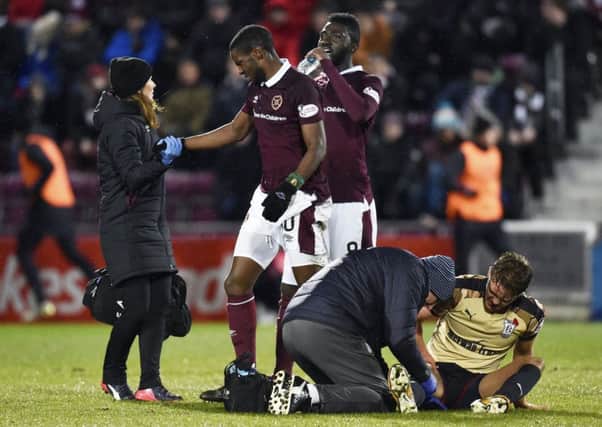Arnaud Djoum is helped to his feet by the Hearts physio after suffering an injury against Dundee. Pic: SNS